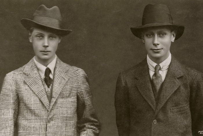Two young men pose wearing suits and hats, standing against a plain background. The text reads "Photo Reveley."