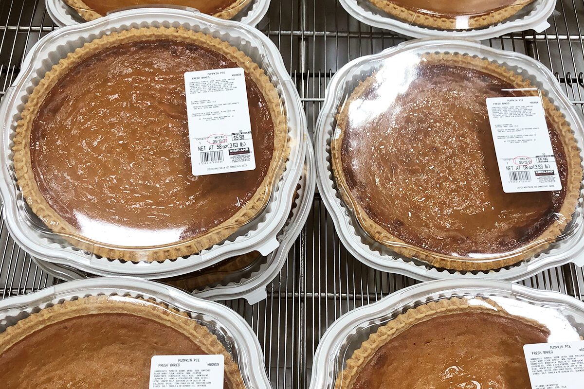 Pumpkin pies sit displayed in clear plastic containers on metal shelves, each labeled "FRESH PUMPKIN PIE" with a price of $5.99.