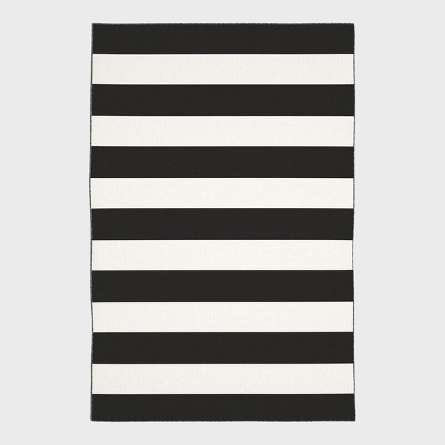 A rectangular rug displays alternating black and white horizontal stripes against a plain gray background.