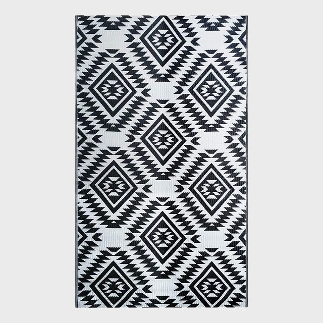 Geometric rug displays diamond patterns with zigzag designs, featuring black and white colors in a symmetrical arrangement.