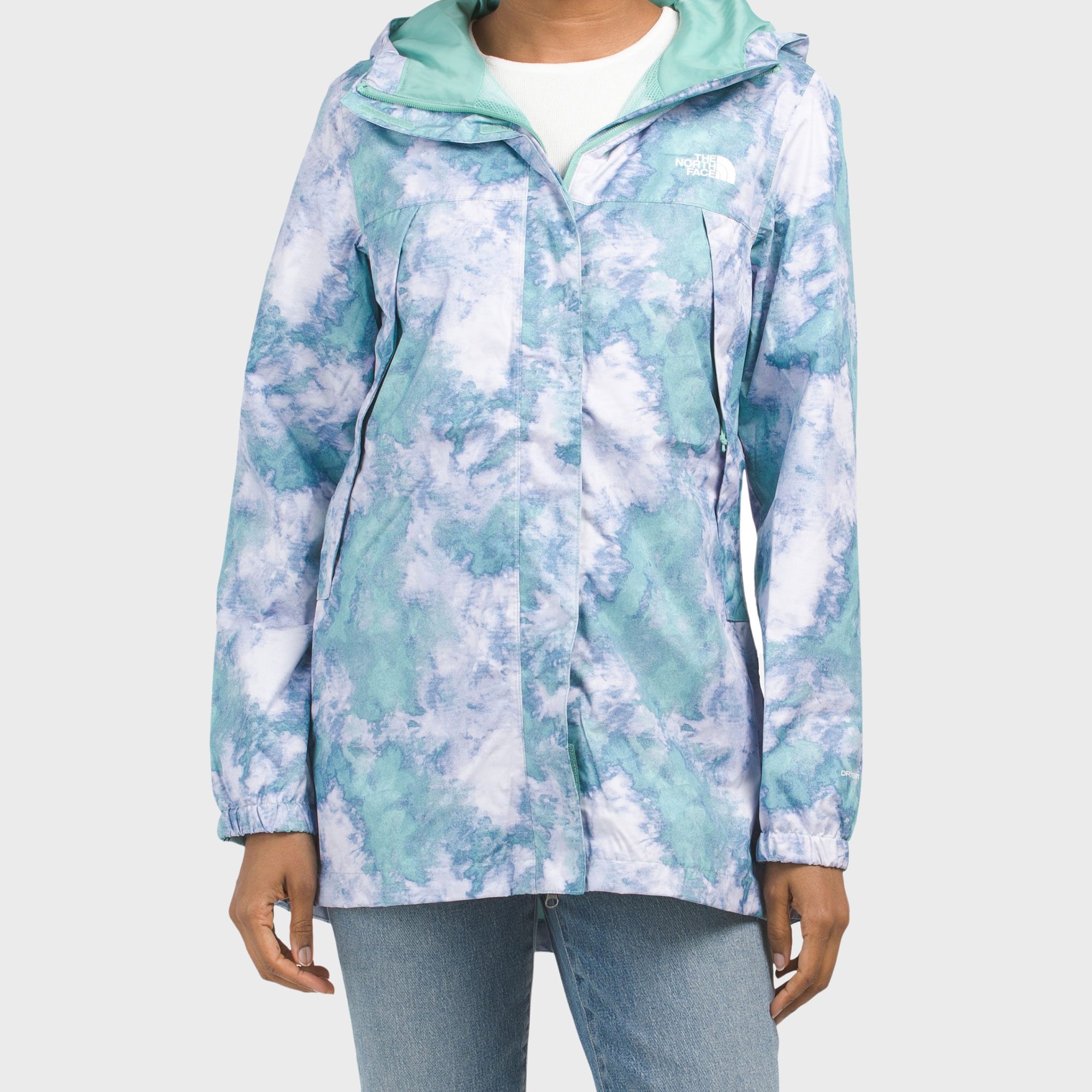 A person wears a turquoise and white patterned jacket with a hood, standing against a plain background. Text: "The North Face."