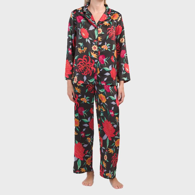 Person wearing colorful floral pajamas, standing barefoot against a plain, light background.