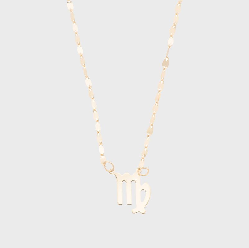 Gold necklace displays Virgo symbol, hangs against plain light background.
