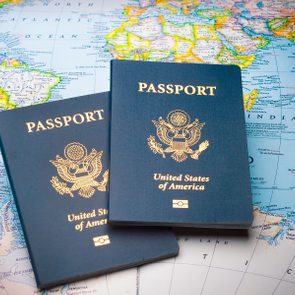 Two US passports rest on a colorful world map, indicating international travel intent.