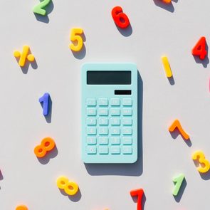 A blue calculator lies among colorful, scattered magnetic numbers on a light background.
