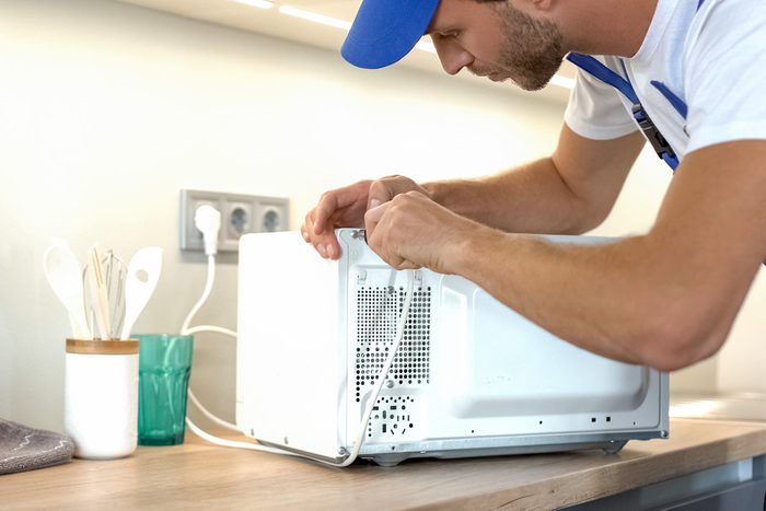 technician fixing microwave