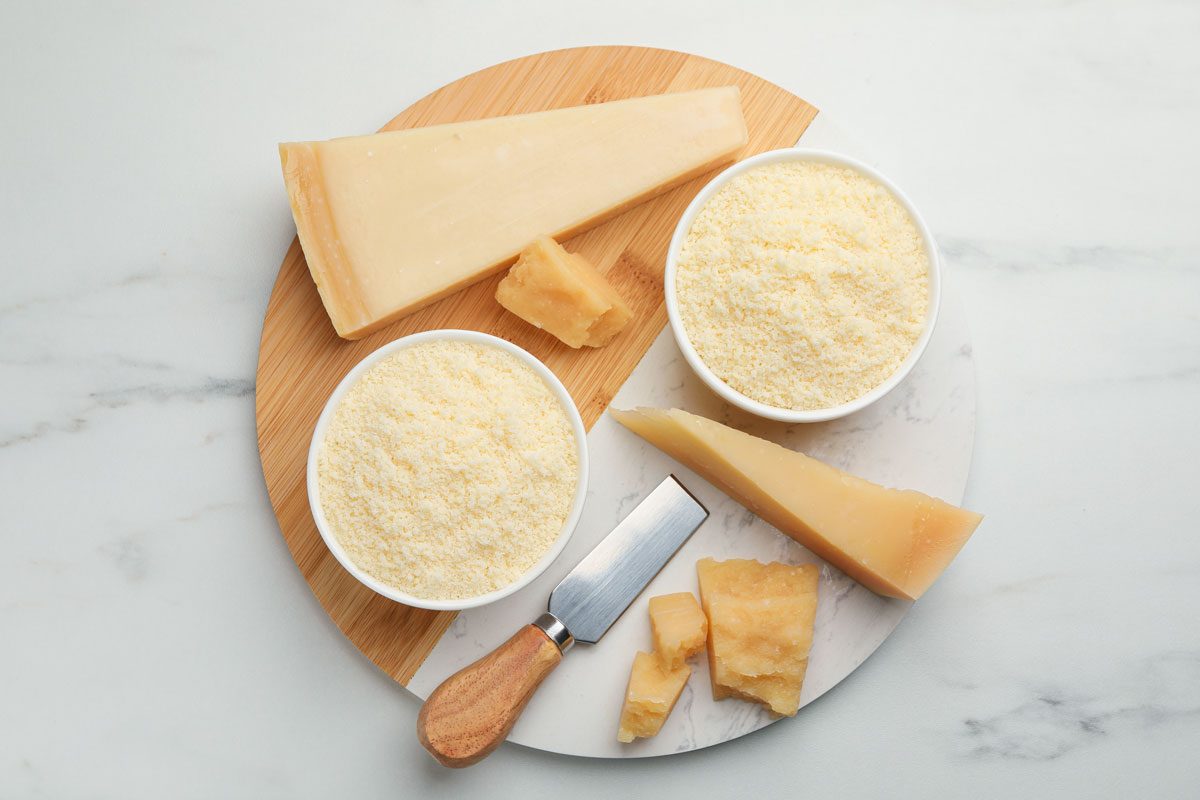 Whole And Grated Parmesan Cheese On White Marble Table
