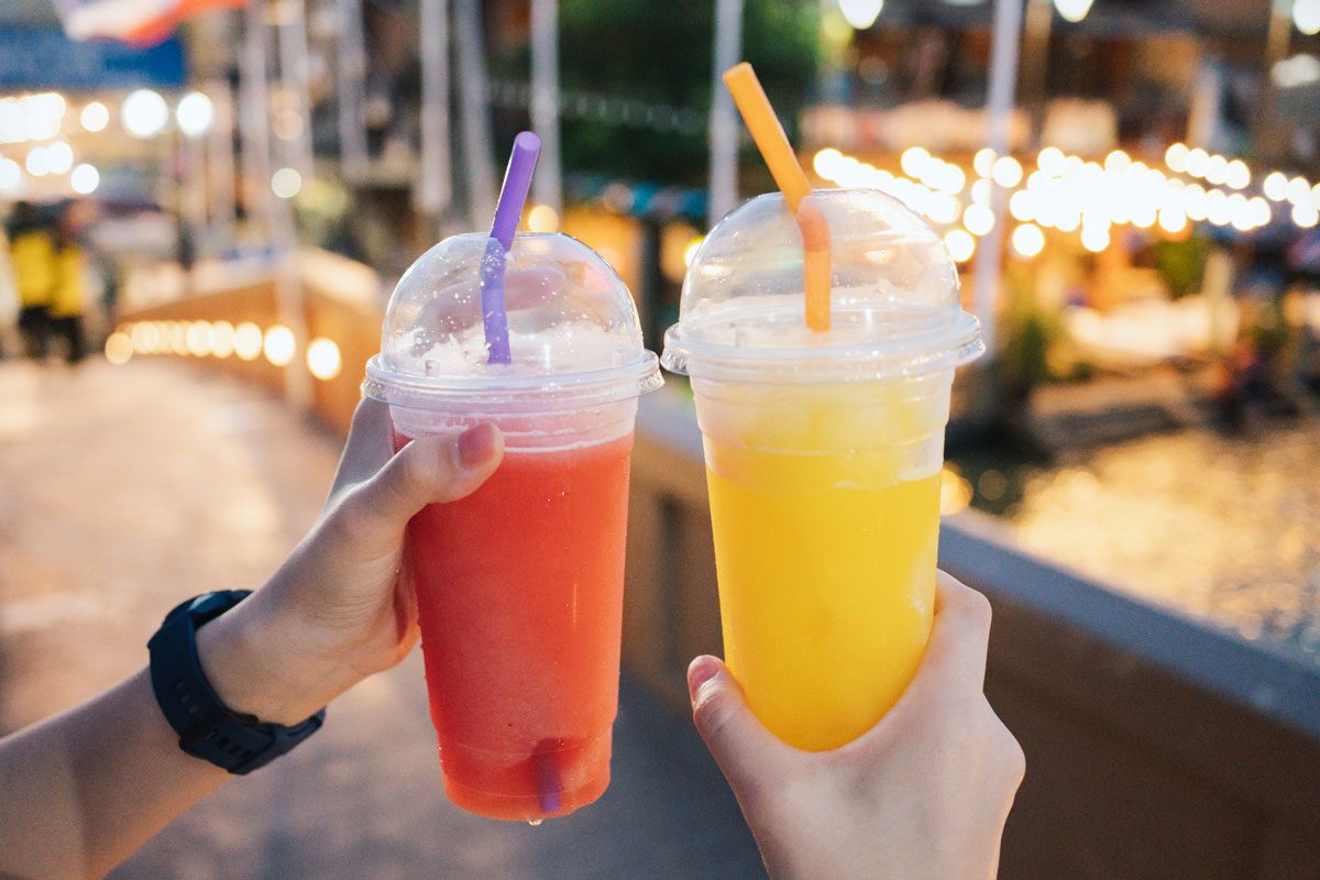 Close Up Hand With Watermelon Juice And Mango Juice In Plastic Cups