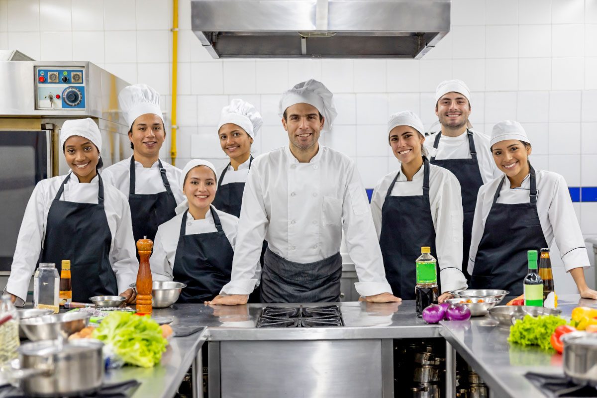 Chefs wearing different hats smiling 