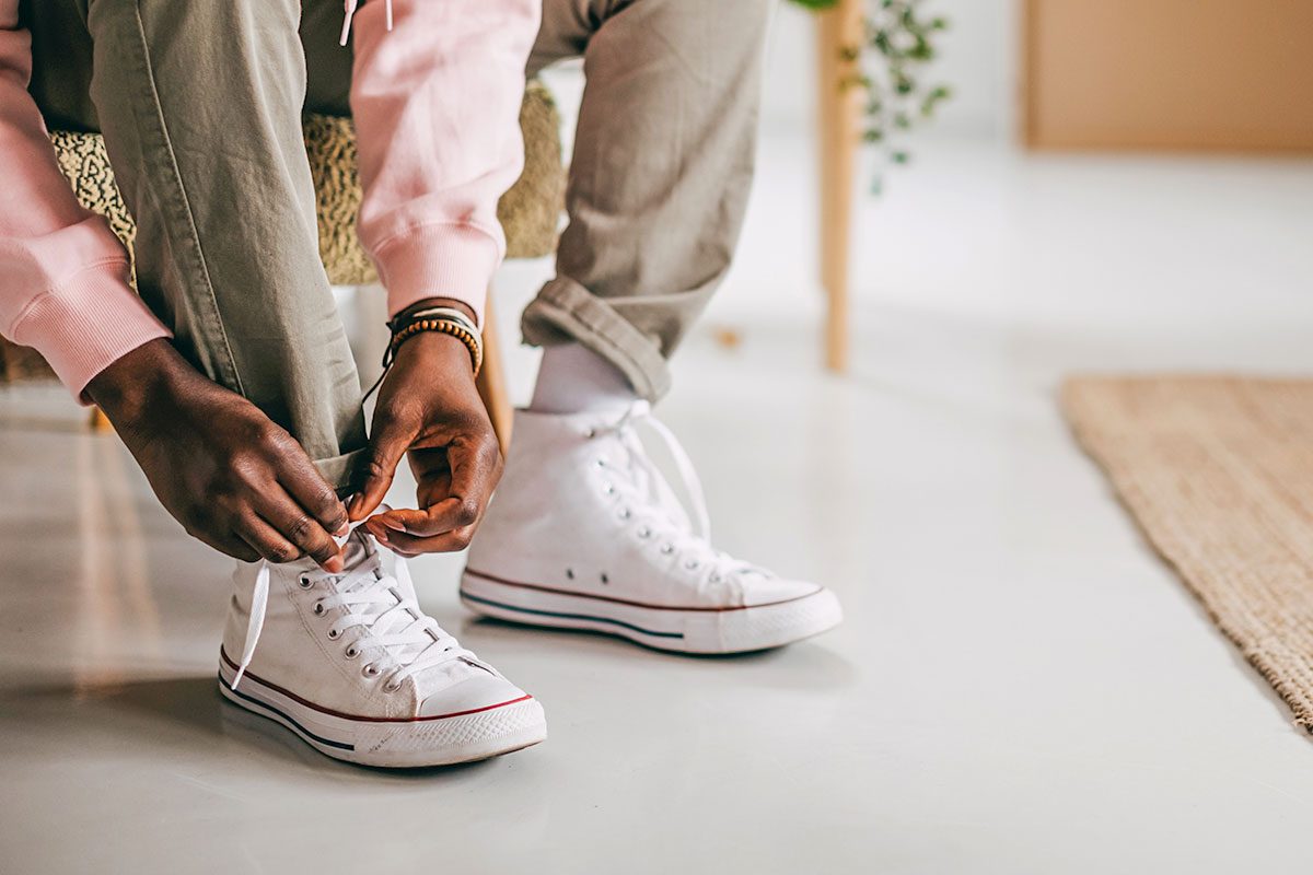 Close up man put on casual sneakers and tie shoelaces on the couch